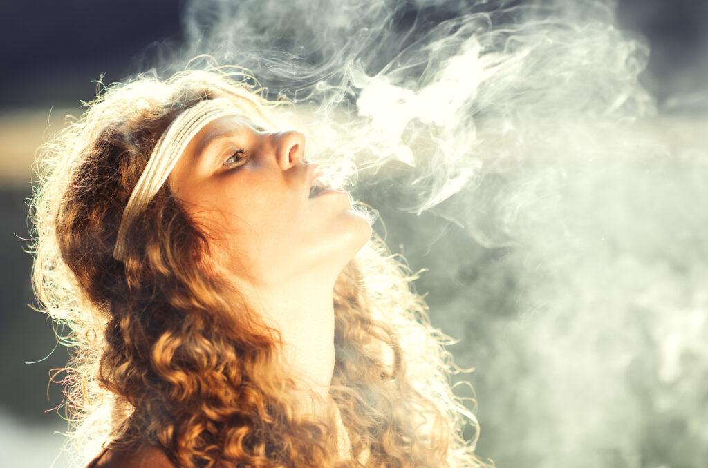 Beautiful free hippie girl blowing smoke.